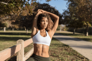 Woman in sports bra stretching at park