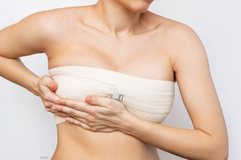 Woman wearing post-surgical bandages over her breasts.