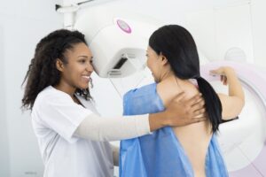 Smiling technician helping a woman as she has a mammogram performed