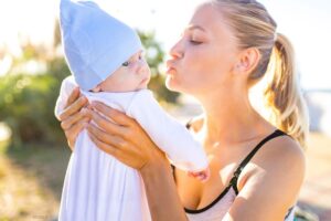 Young mother holding up her baby outside.