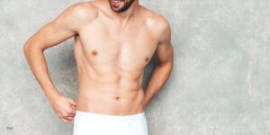 shirt less male standing behind studio background