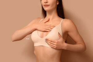 Woman in a tan bra hold her breasts