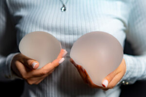 a woman holding two different breast implants